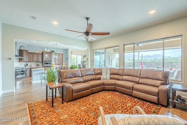 living area with light wood finished floors, recessed lighting, visible vents, a ceiling fan, and beverage cooler