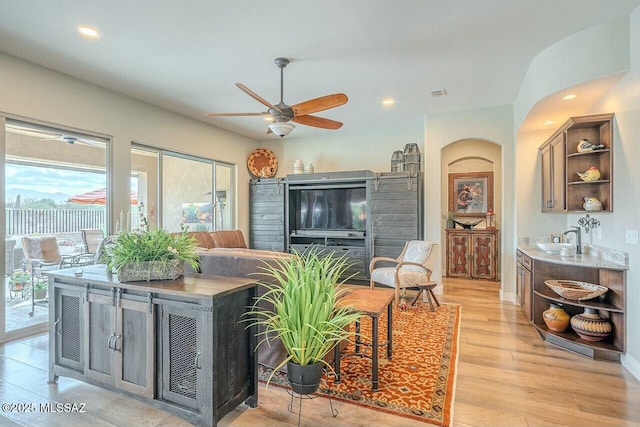 living room featuring a ceiling fan, light wood-type flooring, baseboards, and recessed lighting