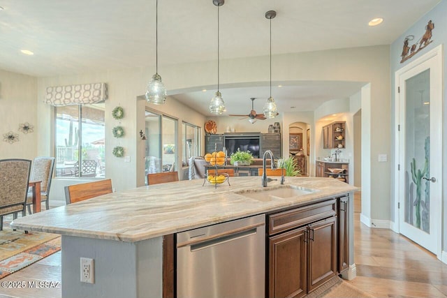 kitchen featuring dishwasher, light wood-style flooring, open floor plan, decorative light fixtures, and a sink