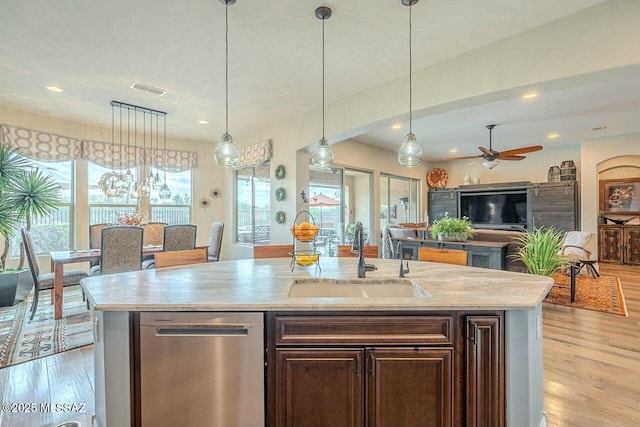 kitchen featuring visible vents, dishwasher, an island with sink, open floor plan, and a sink