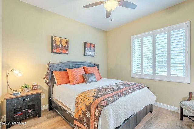 bedroom featuring a ceiling fan, baseboards, and wood finished floors