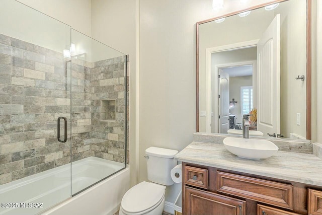 full bath with toilet, bath / shower combo with glass door, and vanity