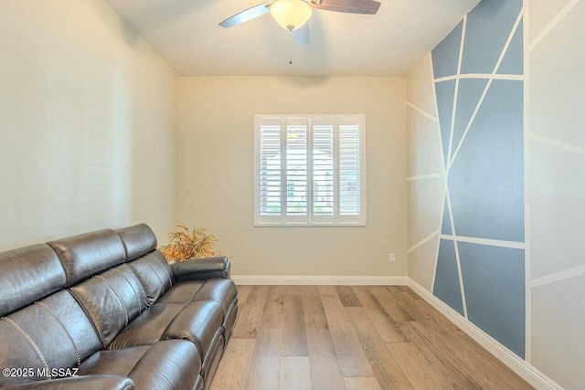 living area featuring a ceiling fan, baseboards, and wood finished floors