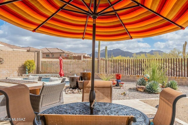 view of patio with outdoor dining area, a fenced backyard, and a mountain view