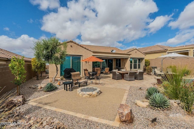 rear view of house featuring a fire pit, fence, a tile roof, stucco siding, and a patio area