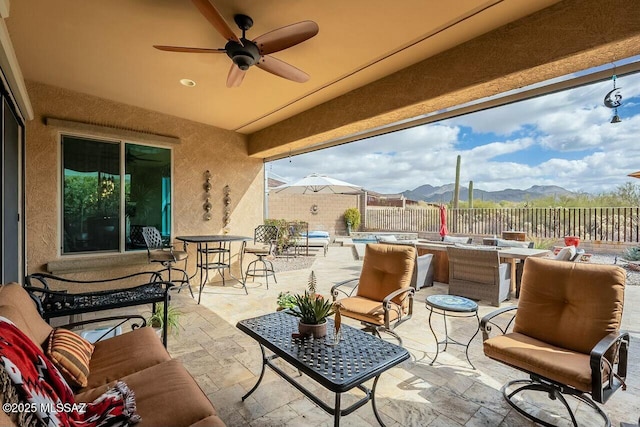 view of patio / terrace with outdoor lounge area, outdoor dining space, ceiling fan, a mountain view, and fence