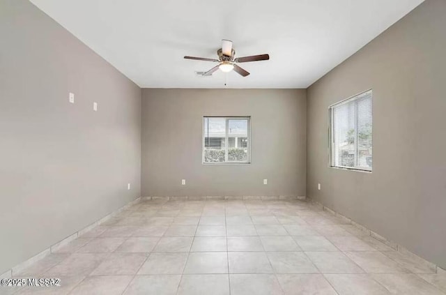 spare room featuring light tile patterned floors, ceiling fan, and a wealth of natural light