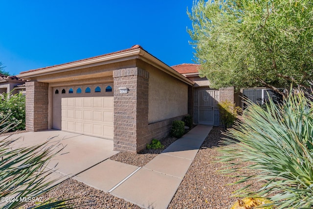 view of home's exterior featuring stucco siding, driveway, a tile roof, and a garage