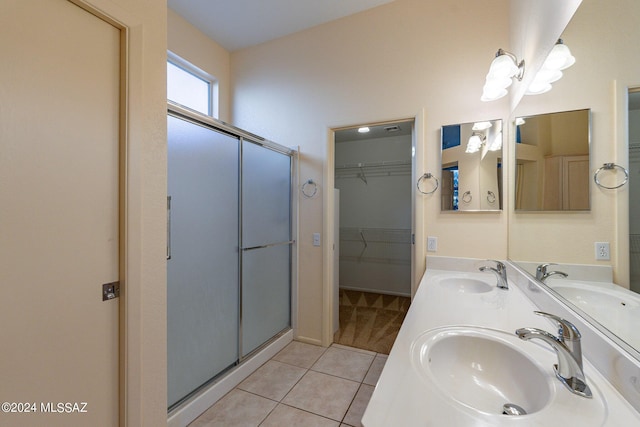 bathroom with a walk in closet, tile patterned floors, a stall shower, and a sink