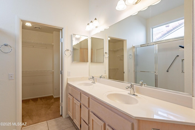 full bathroom featuring tile patterned flooring, double vanity, a shower with shower door, and a sink