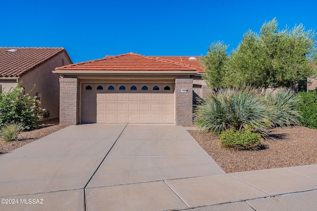 view of front of property featuring a tiled roof, a garage, driveway, and stucco siding