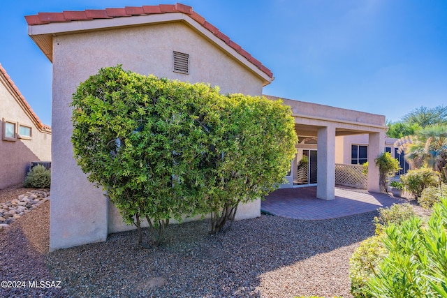 rear view of property featuring stucco siding, a tile roof, and a patio area