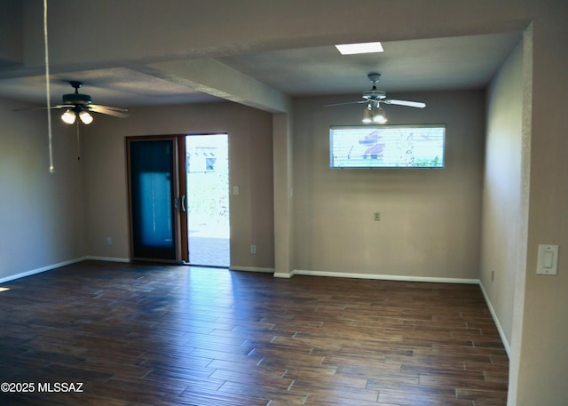 spare room with baseboards, dark wood-style flooring, and a ceiling fan