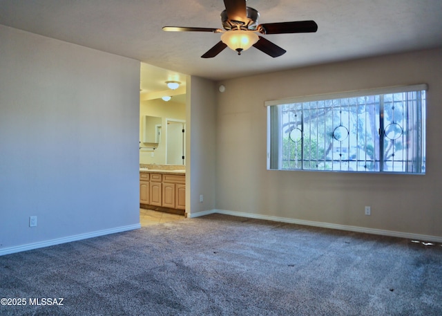 empty room with light colored carpet, baseboards, and a ceiling fan