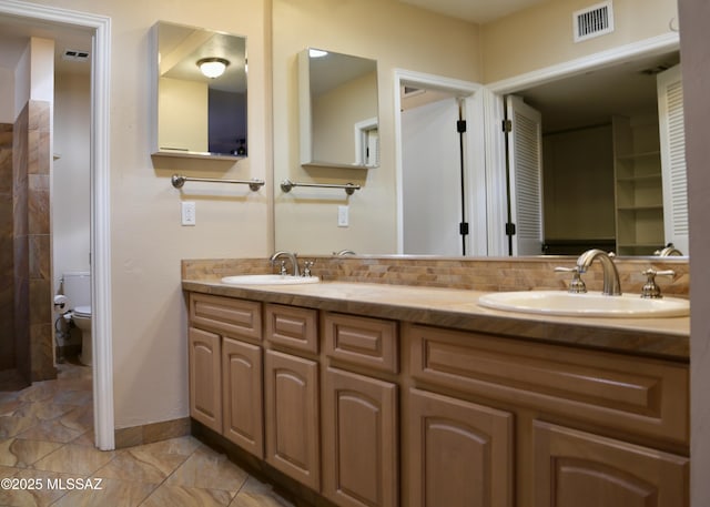 full bath with a sink, visible vents, backsplash, and toilet