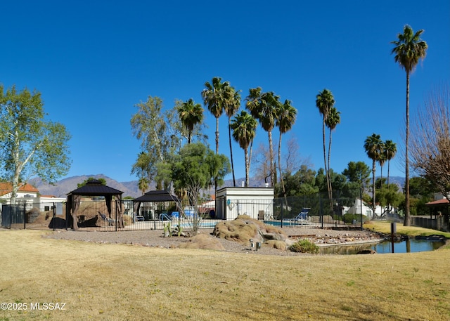 surrounding community featuring a gazebo, a water view, a lawn, and fence