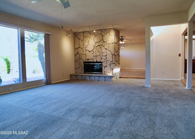 unfurnished living room featuring a stone fireplace, carpet, and ceiling fan