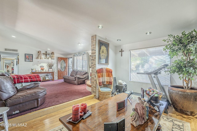 living room featuring lofted ceiling, visible vents, a wealth of natural light, and wood finished floors