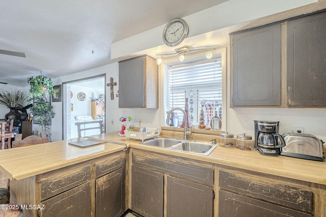 kitchen with a peninsula, light countertops, and a sink