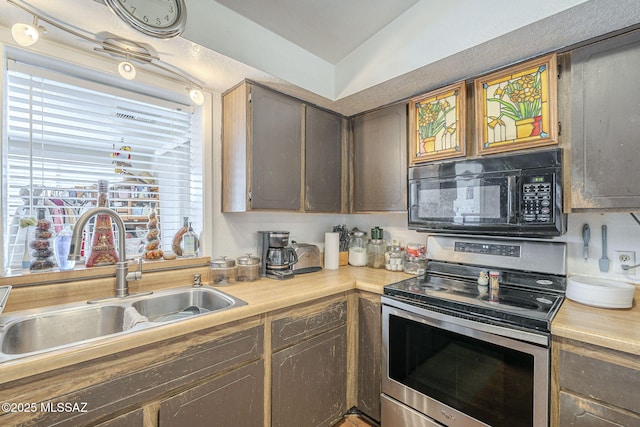 kitchen with black microwave, electric stove, a sink, and light countertops