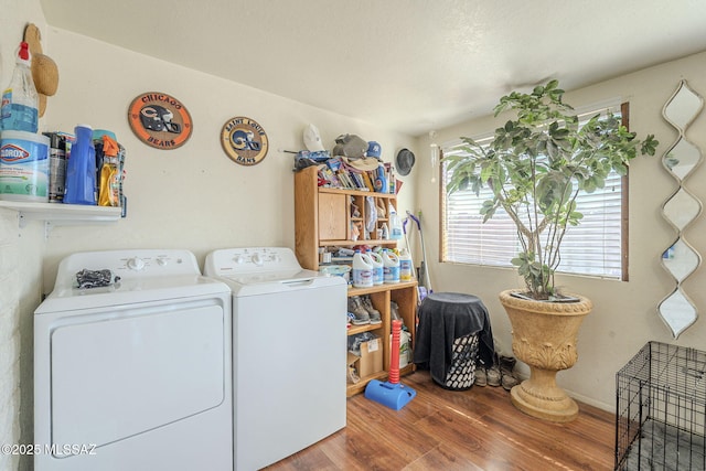 clothes washing area with washer and dryer, laundry area, baseboards, and wood finished floors