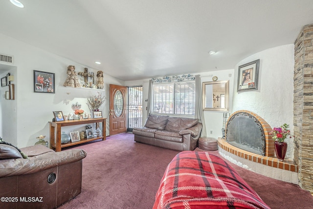 living room with a fireplace with raised hearth, carpet, and visible vents