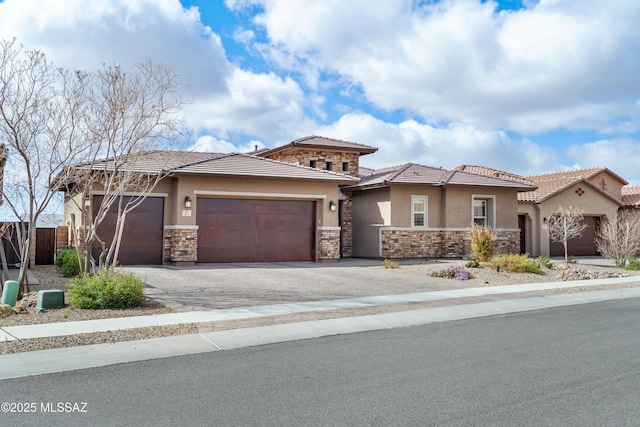 prairie-style house featuring an attached garage, stone siding, a tiled roof, driveway, and stucco siding