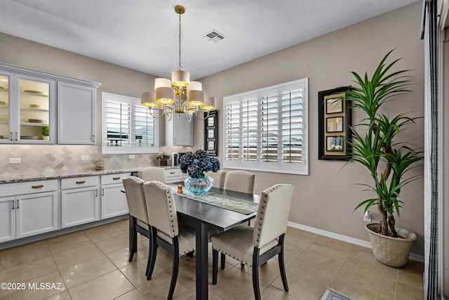 dining space featuring a chandelier, light tile patterned floors, visible vents, and baseboards