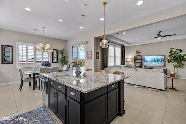 kitchen featuring light tile patterned floors, visible vents, a sink, dark cabinetry, and plenty of natural light