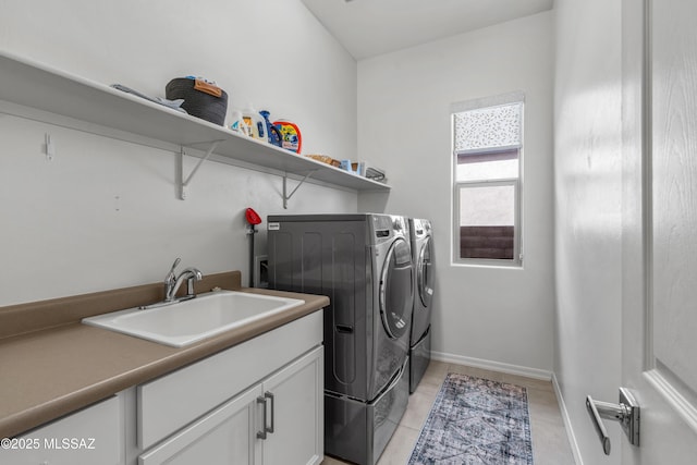 washroom featuring cabinet space, baseboards, washer and dryer, a sink, and light tile patterned flooring