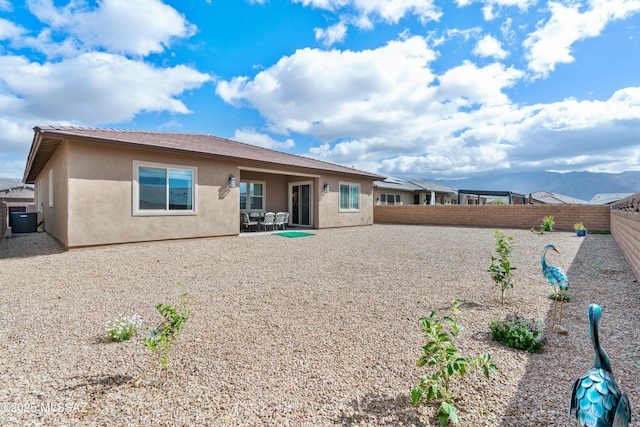 back of house featuring a patio area, a fenced backyard, central AC, and stucco siding