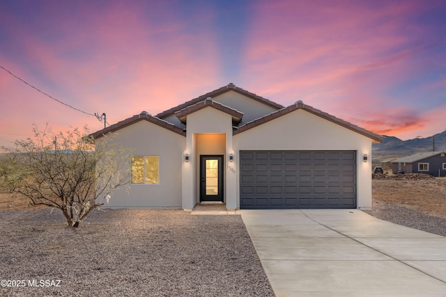 view of front of home with a garage, concrete driveway, a tiled roof, and stucco siding