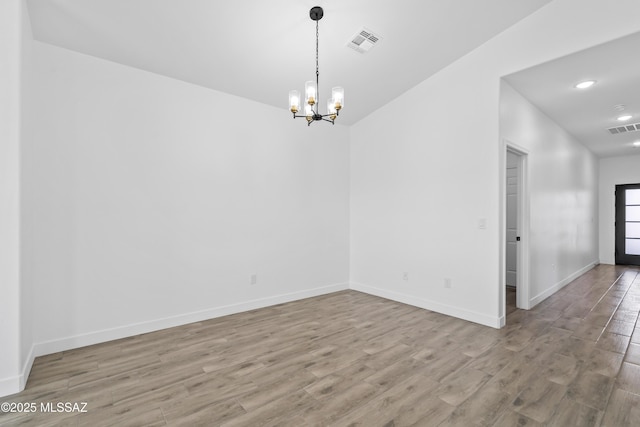 spare room with wood finished floors, visible vents, and baseboards