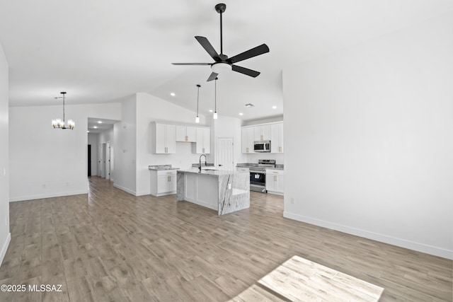 kitchen with stainless steel appliances, open floor plan, a sink, and light wood-style flooring