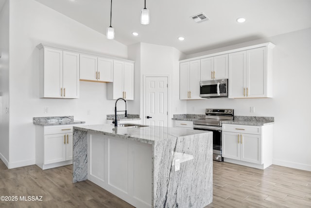 kitchen featuring visible vents, a kitchen island with sink, stainless steel appliances, white cabinetry, and a sink