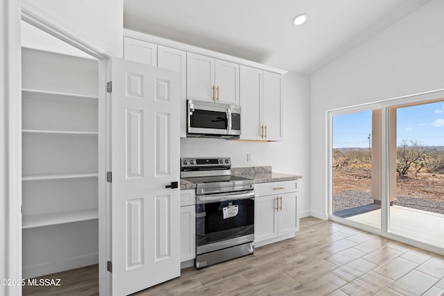 kitchen featuring appliances with stainless steel finishes, white cabinets, light wood-style floors, and baseboards