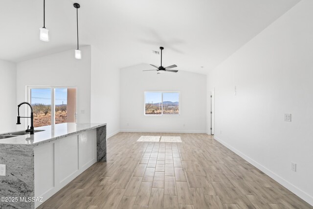 unfurnished living room featuring ceiling fan, high vaulted ceiling, a sink, baseboards, and light wood finished floors