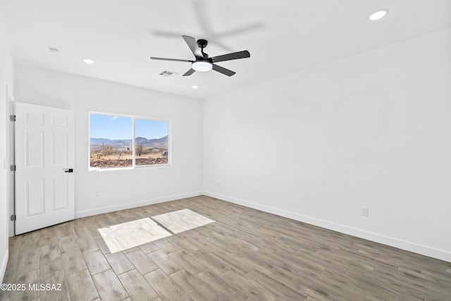 unfurnished room with ceiling fan, recessed lighting, wood finished floors, visible vents, and baseboards