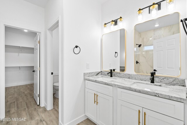 full bathroom featuring toilet, double vanity, walk in shower, and a sink