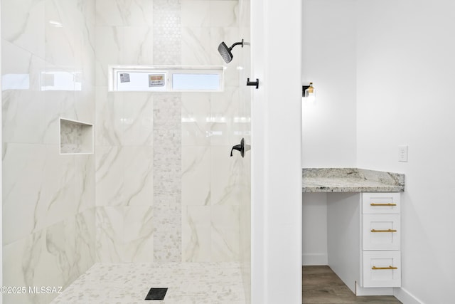 full bath with wood finished floors, a tile shower, and baseboards