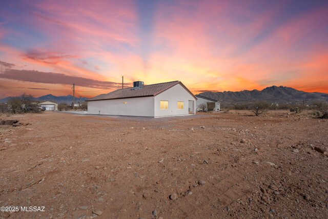 view of property exterior with central AC unit, a tile roof, a mountain view, and stucco siding