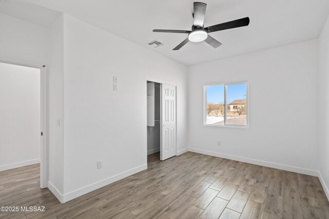 unfurnished bedroom featuring baseboards, a closet, visible vents, and wood finished floors