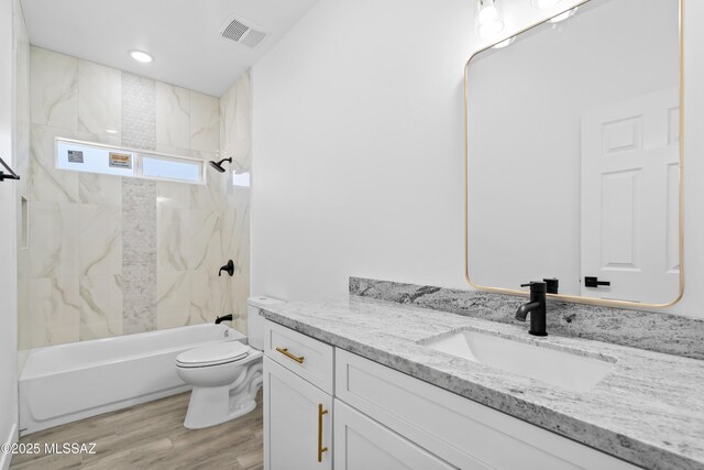 full bath with bathtub / shower combination, toilet, wood finished floors, vanity, and visible vents