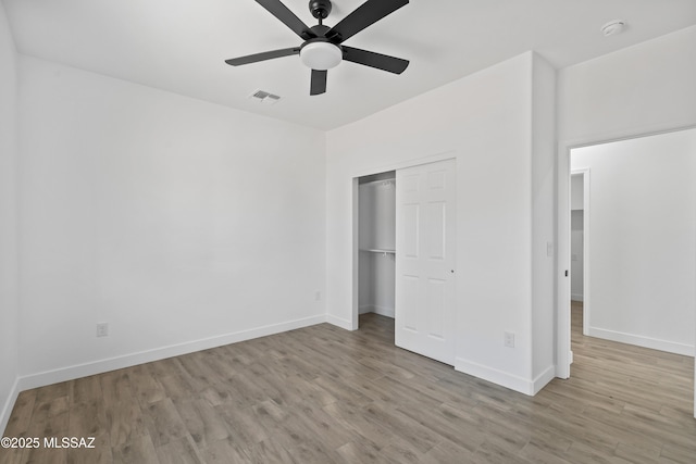 unfurnished bedroom with a closet, visible vents, baseboards, and wood finished floors