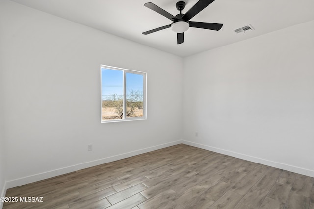 empty room with a ceiling fan, visible vents, baseboards, and wood finished floors