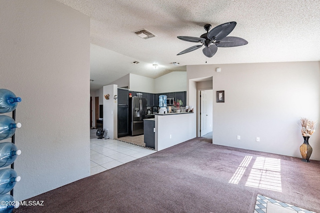 kitchen featuring lofted ceiling, visible vents, light carpet, a textured ceiling, and black fridge