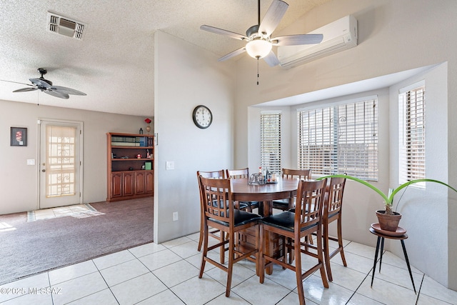 dining space featuring visible vents, an AC wall unit, light carpet, light tile patterned flooring, and a textured ceiling