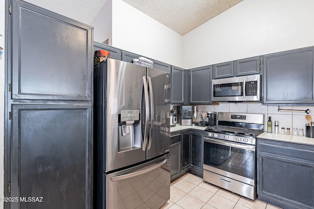 kitchen featuring light tile patterned floors, tasteful backsplash, appliances with stainless steel finishes, light countertops, and a textured ceiling