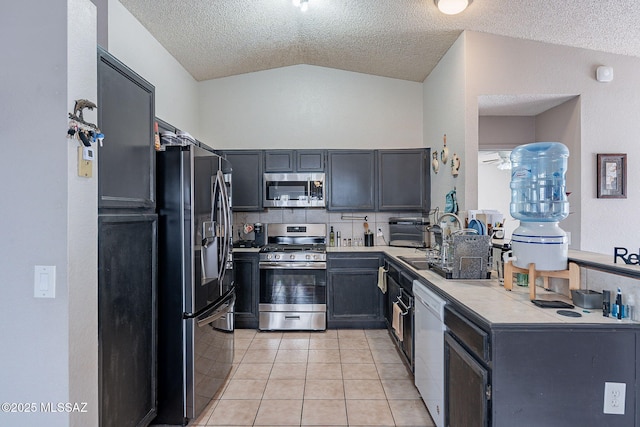 kitchen featuring light tile patterned floors, lofted ceiling, stainless steel appliances, light countertops, and a sink