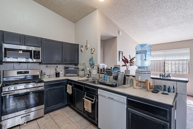 kitchen with tile countertops, light tile patterned floors, tasteful backsplash, appliances with stainless steel finishes, and dark cabinetry